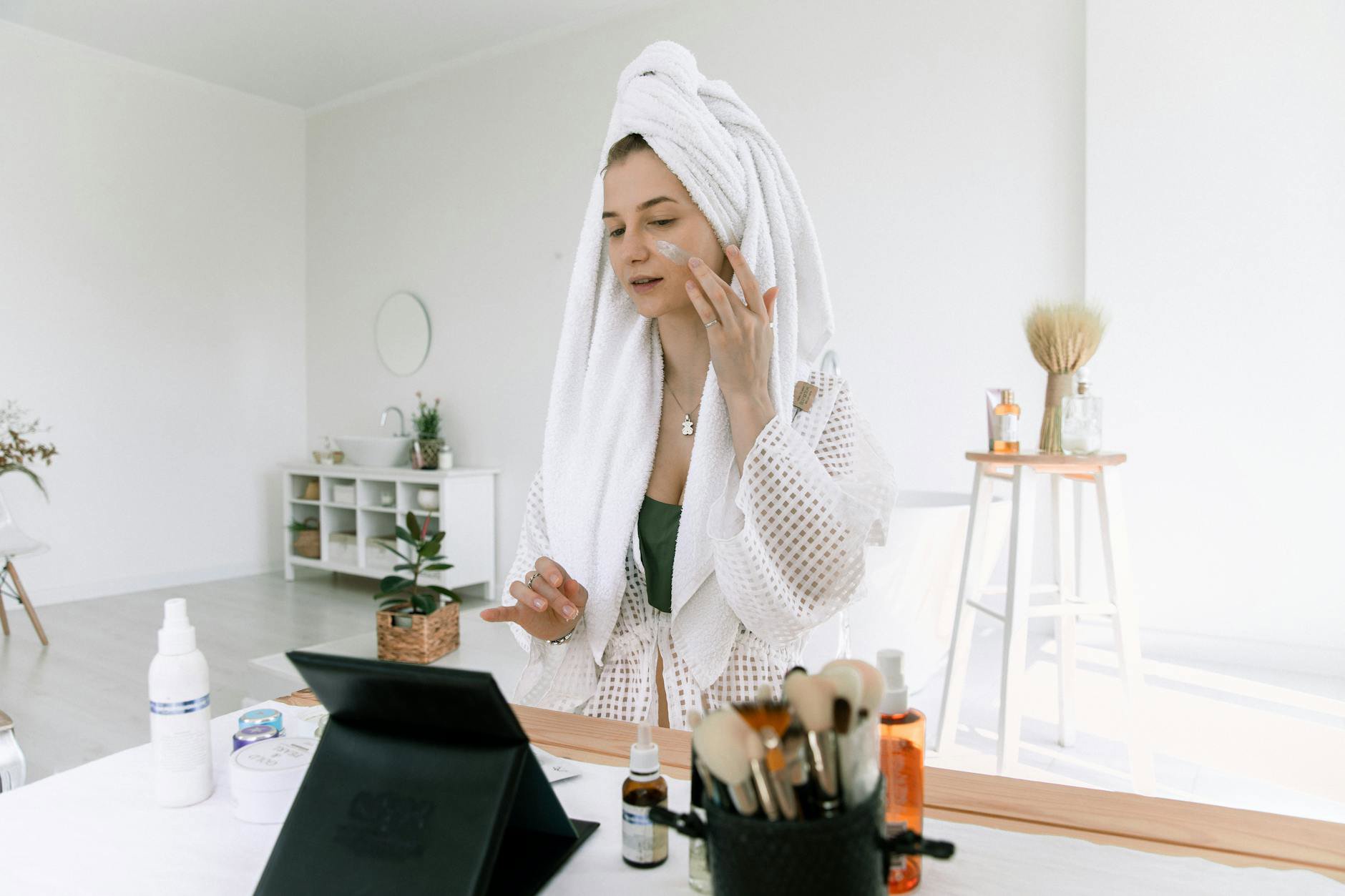 woman applying face serum bathroom mirror