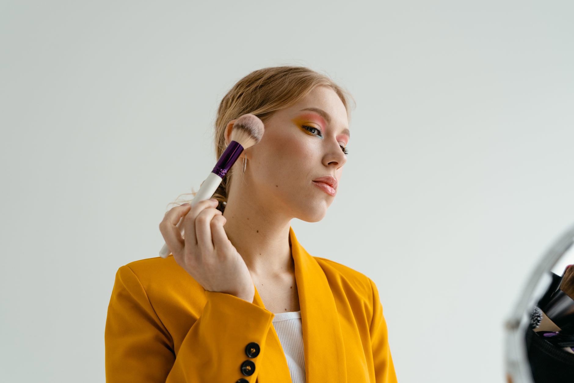 woman applying highlighter cheekbone natural light
