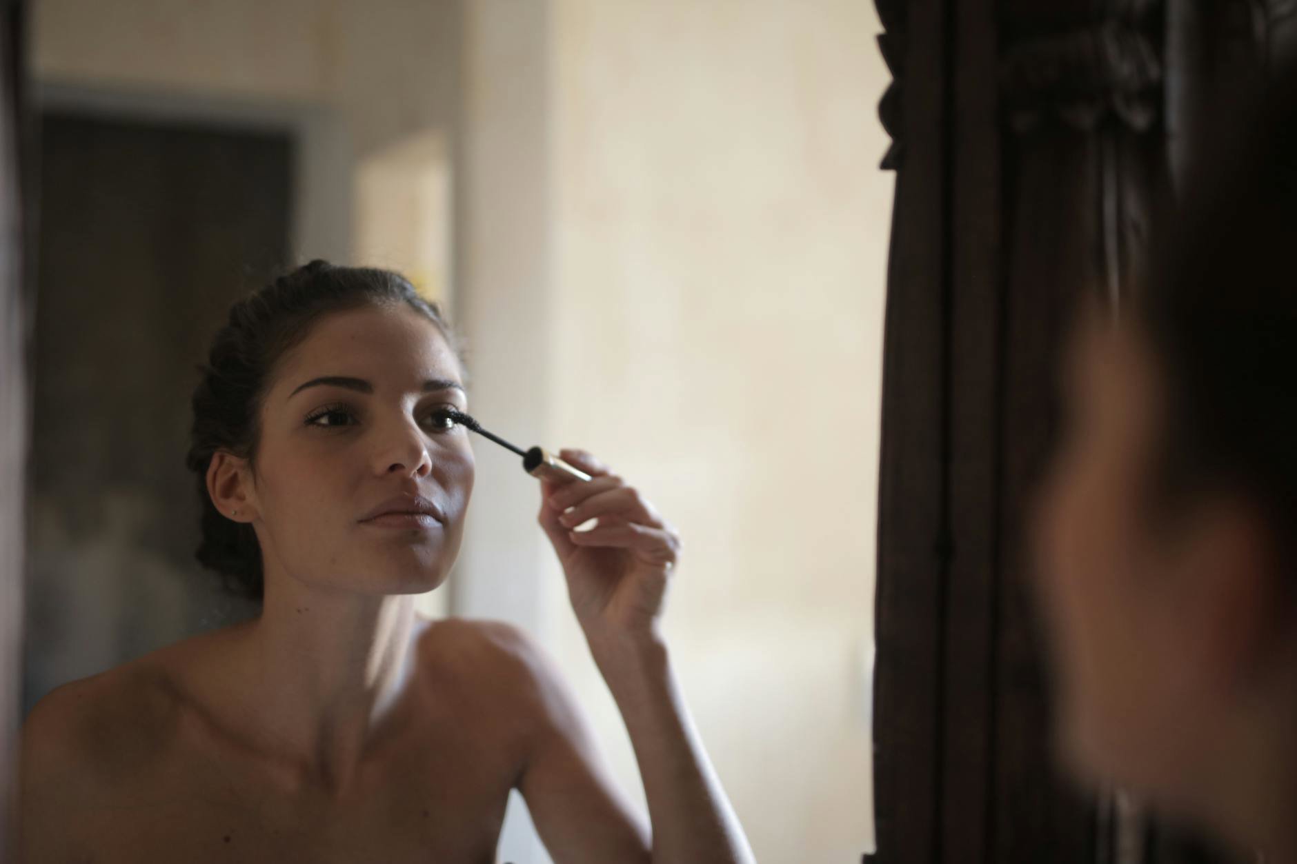 woman applying mascara bathroom mirror