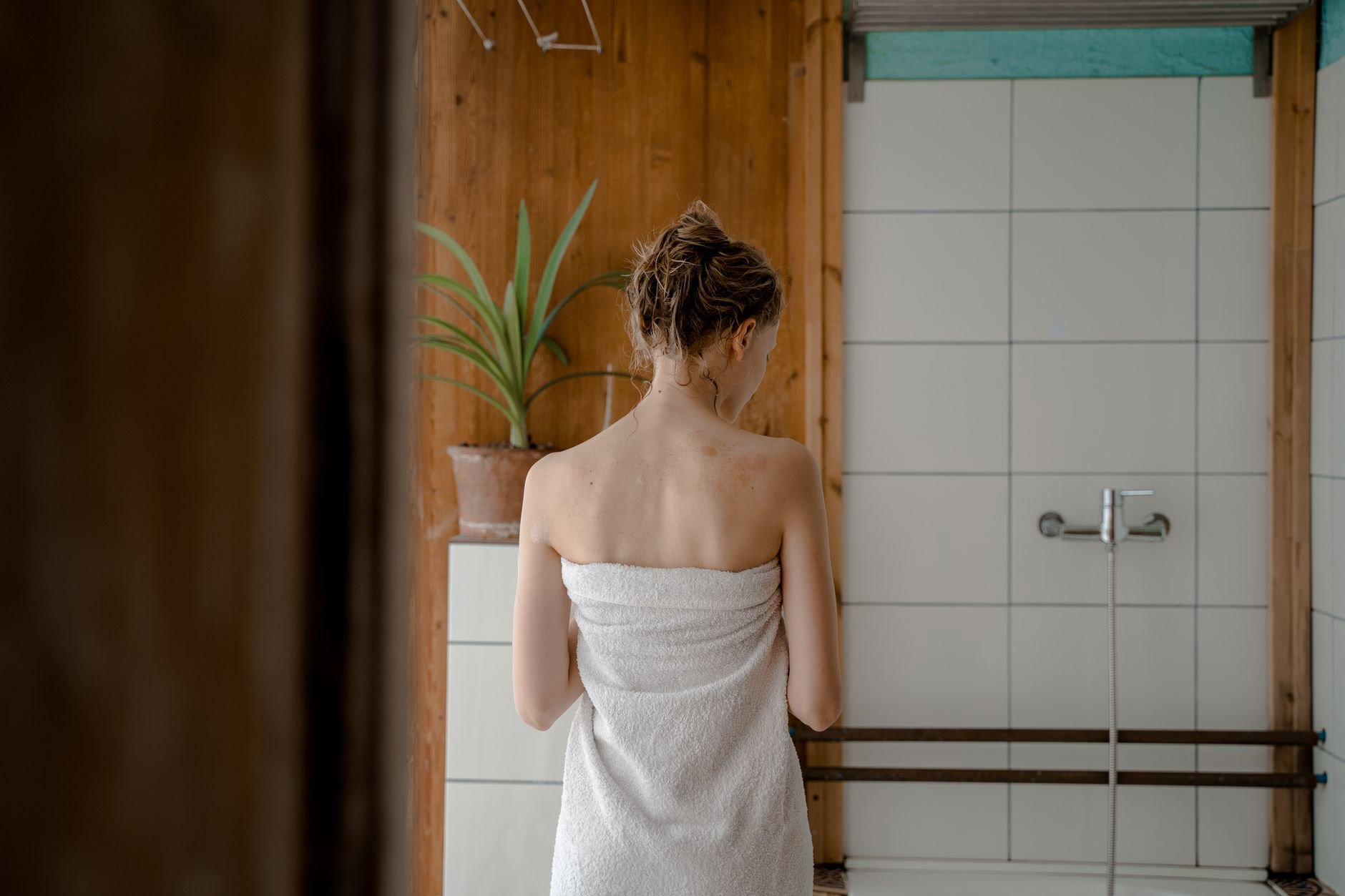 woman towel drying hair after shower in bathroom