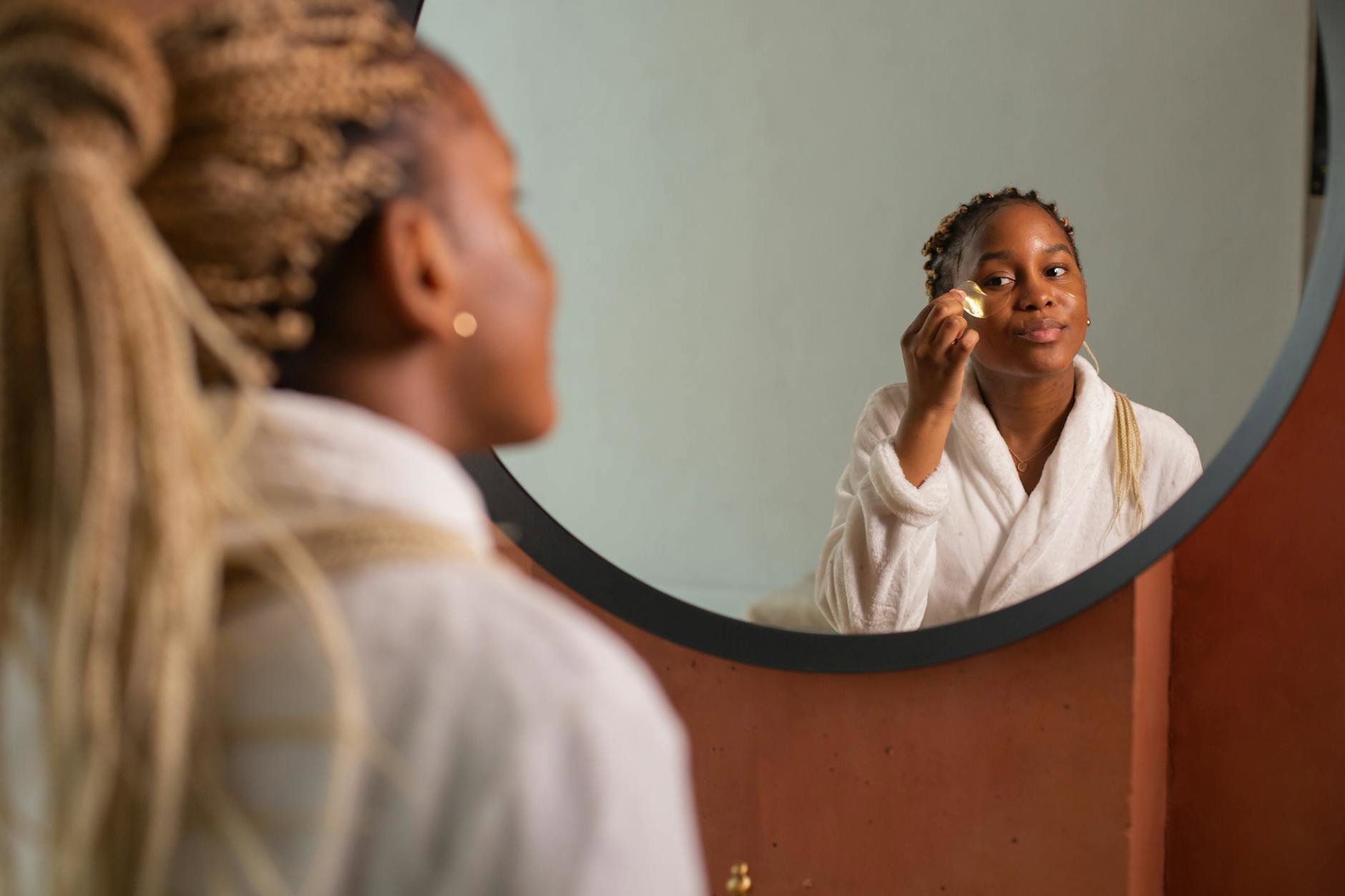 woman applying serum bathroom mirror morning light