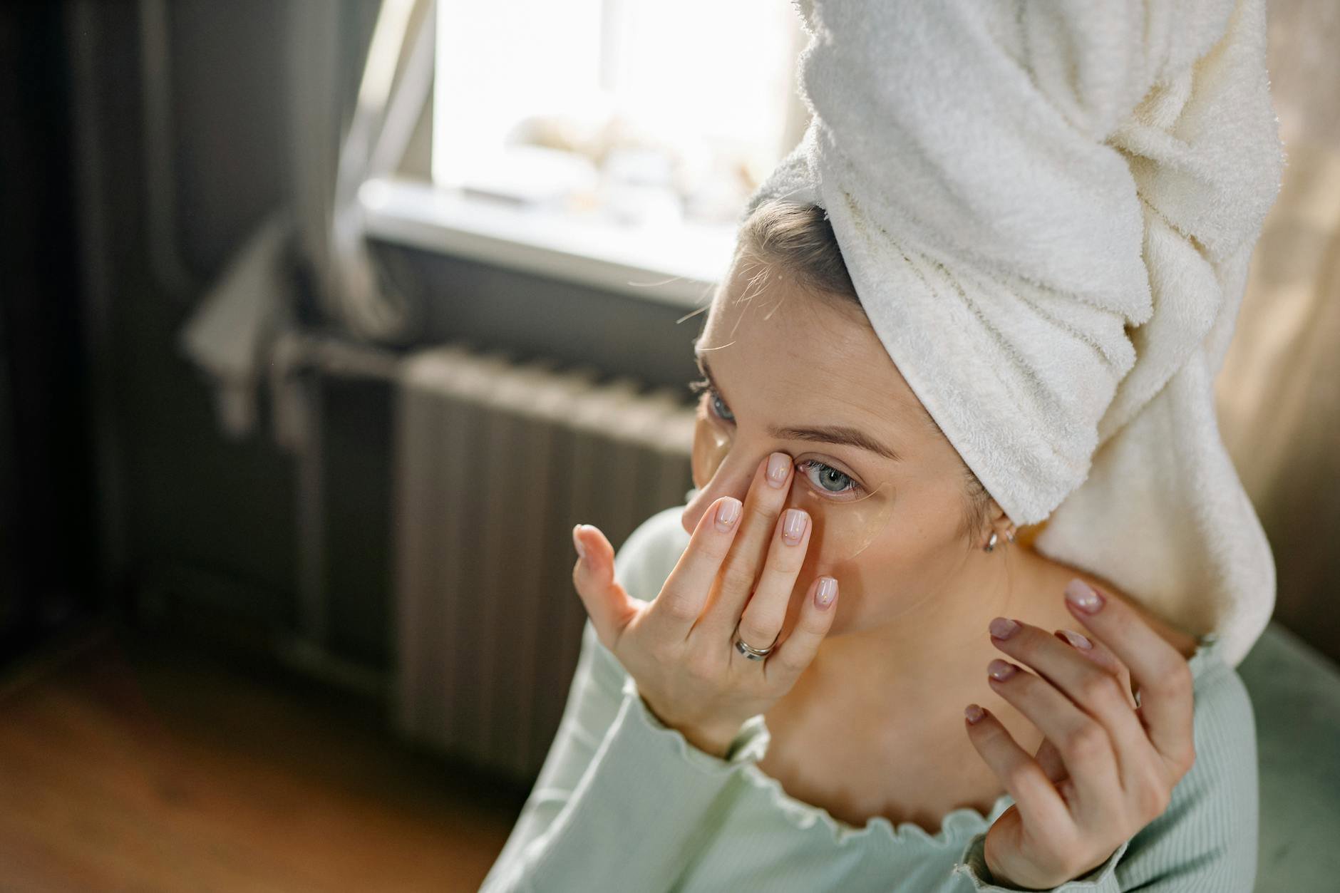 woman applying eye cream cold spoon under eyes