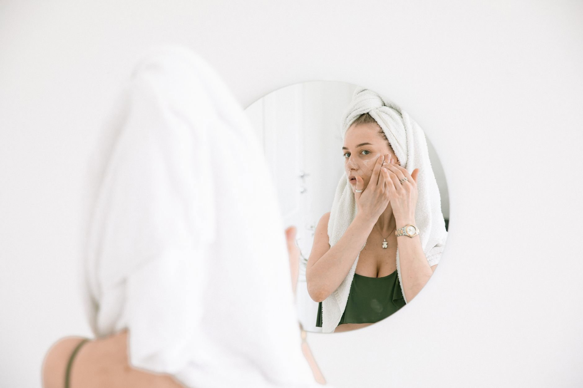 woman applying sunscreen to face morning bathroom mirror