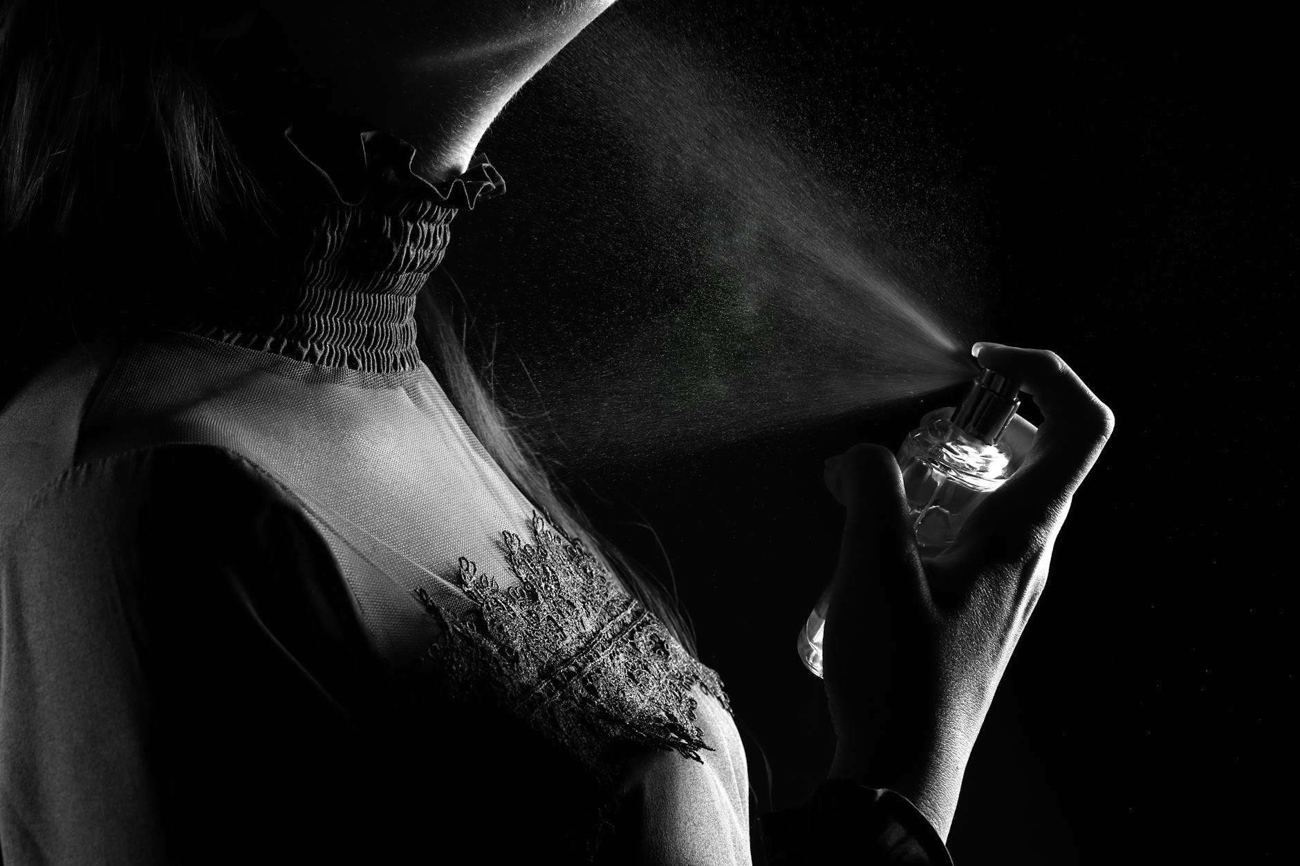 woman spraying perfume on scarf at home