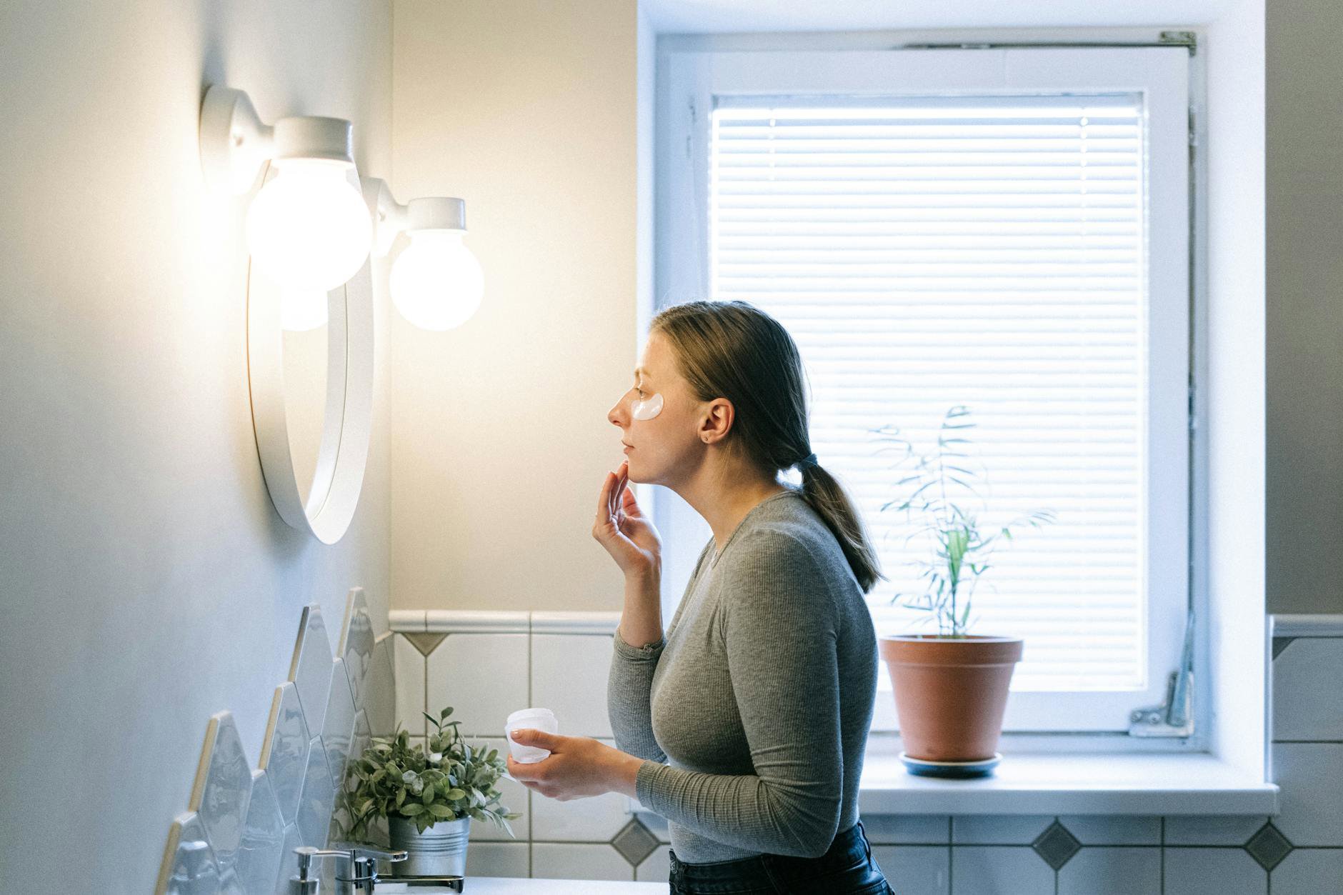 woman applying sunscreen in bathroom mirror