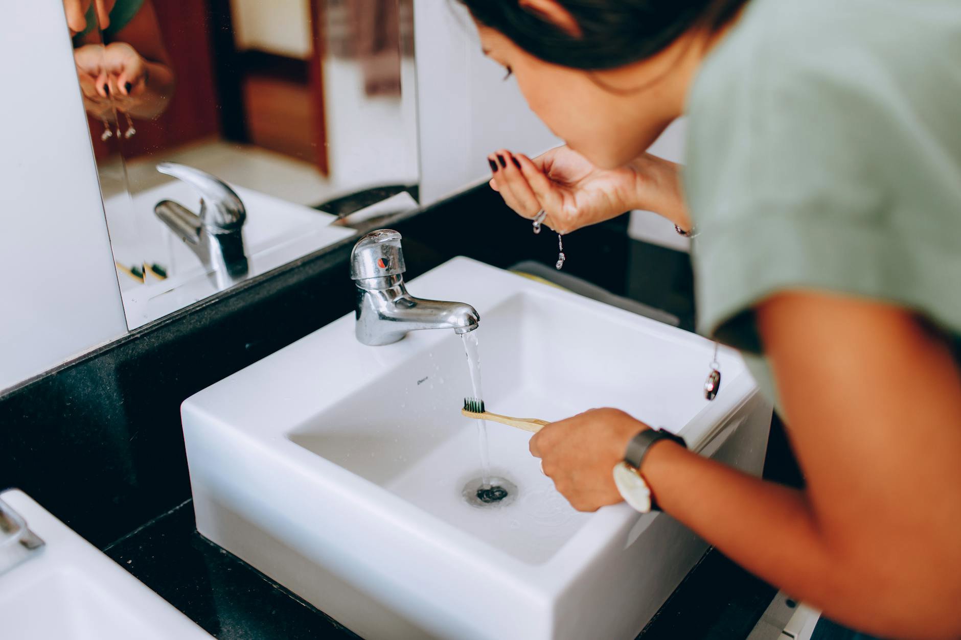 woman cleaning makeup brushes at sink