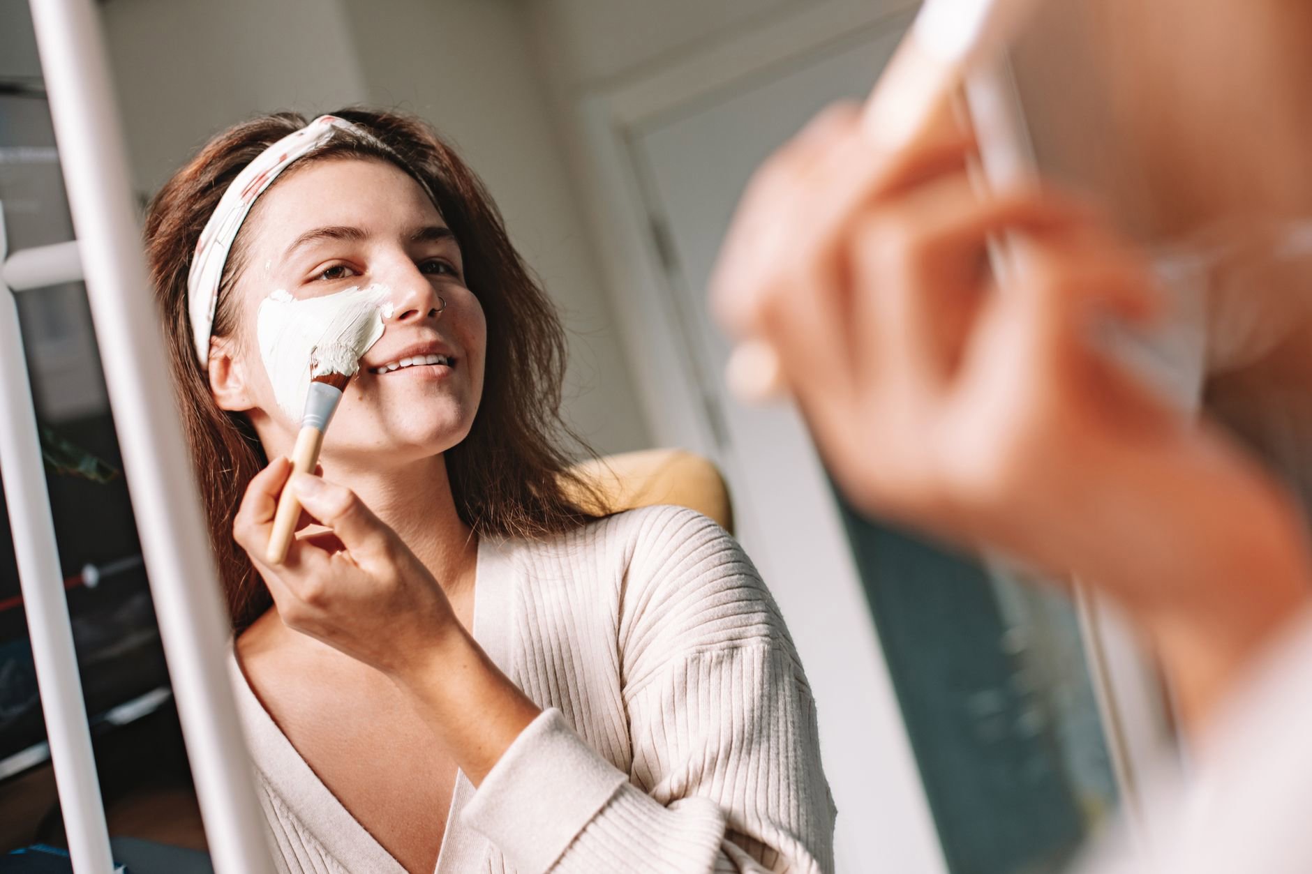 woman applying cream bronzer stick in mirror