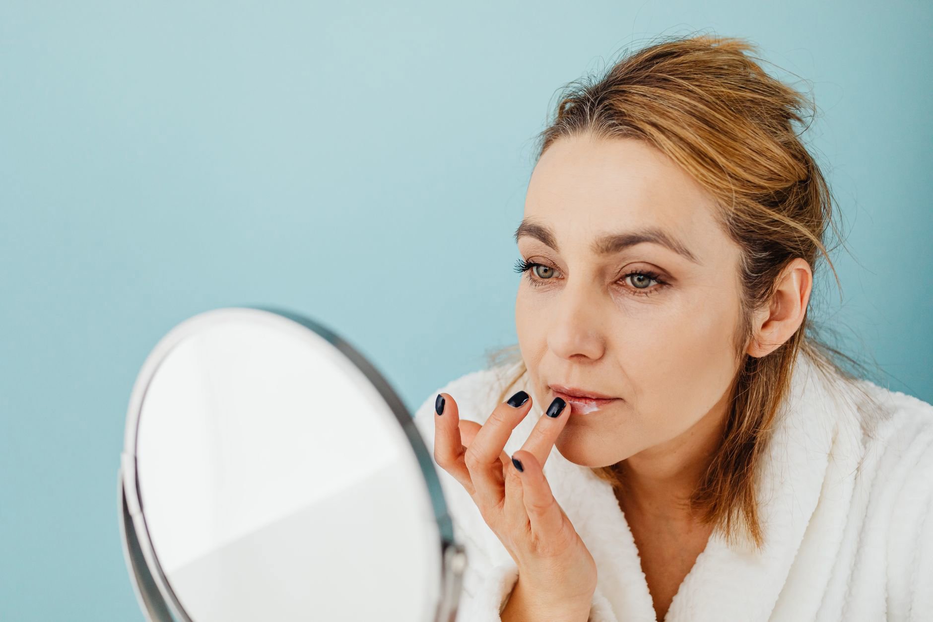 woman applying lip balm mirror