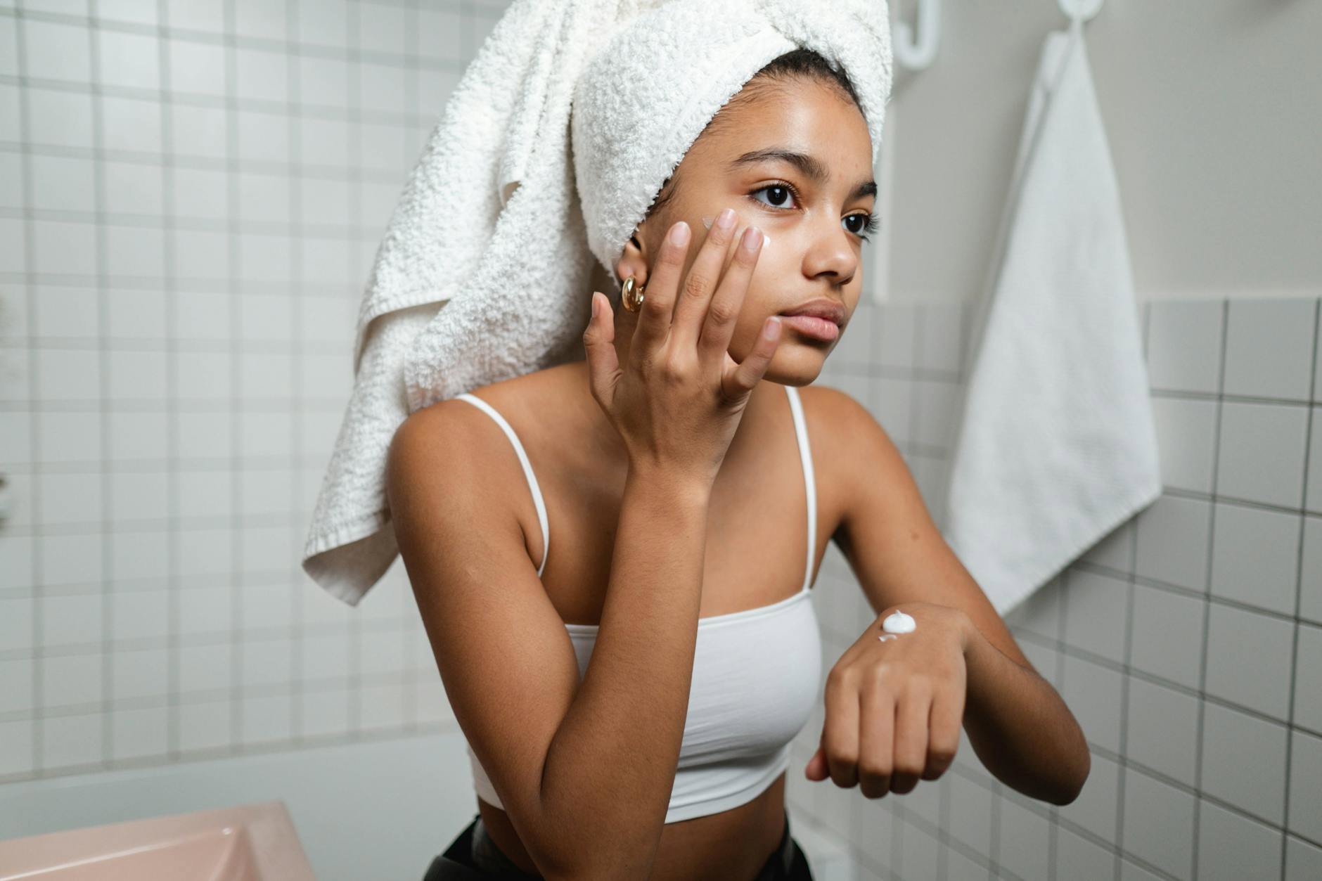 woman applying self tanner on arm bathroom